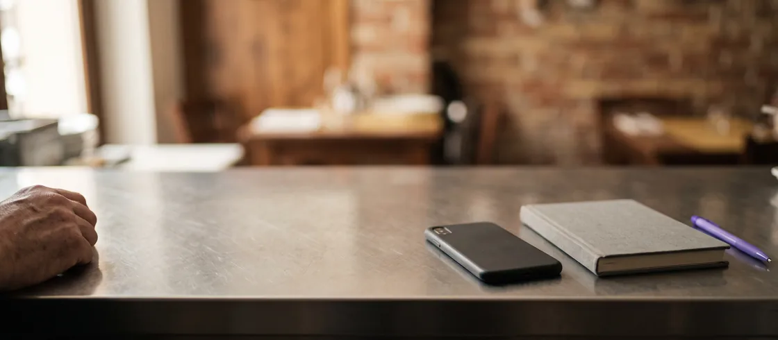 Uno smartphone appoggiato accanto ad alcune note scritte a mano per un ordine fornitore.