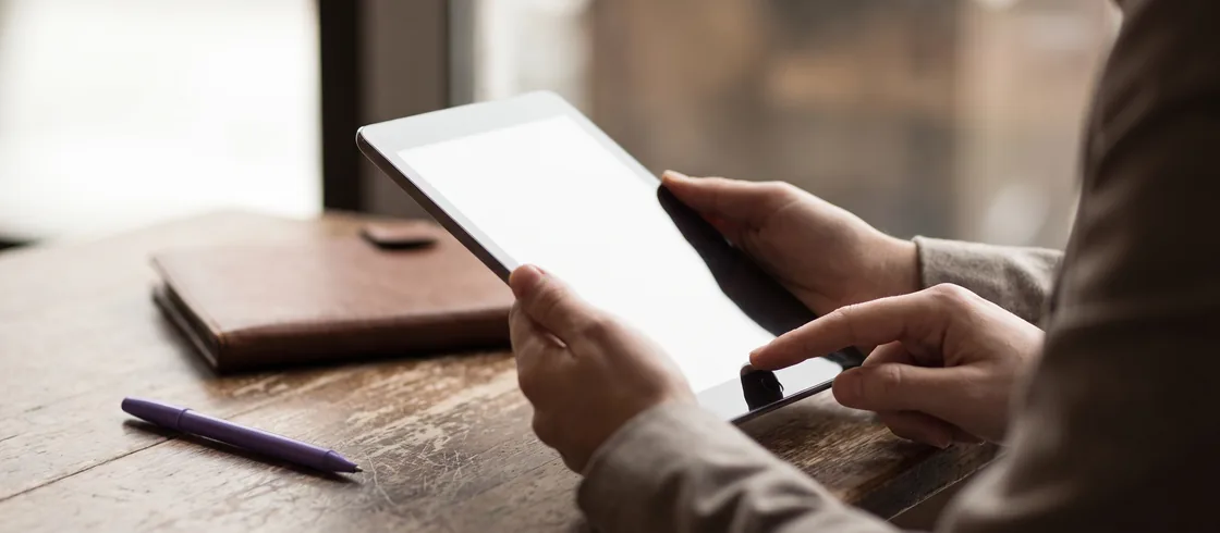 Una mano scorre un riepilogo ordine su tablet, verifica del totale prima dell'invio.