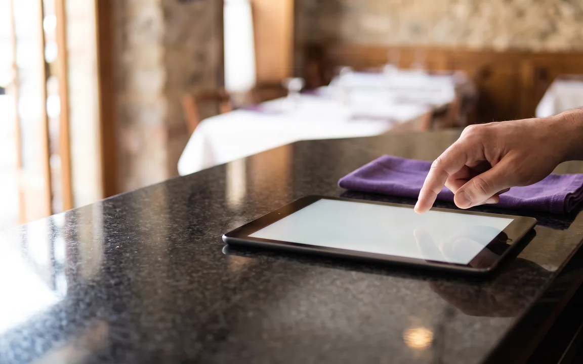 Una responsabile scorre l'elenco delle sedi su tablet prima di aprire l'ordine di una di esse.