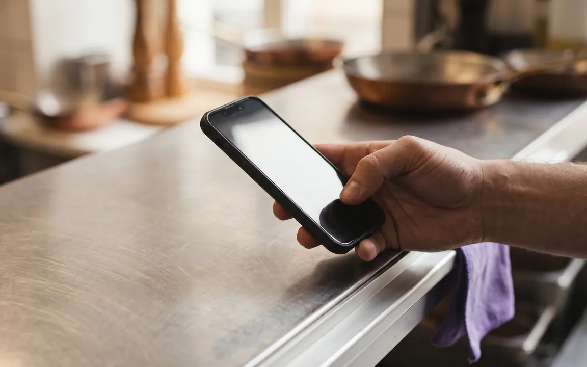 Uno smartphone con il riepilogo di un ordine fornitore appoggiato sul banco della cucina.